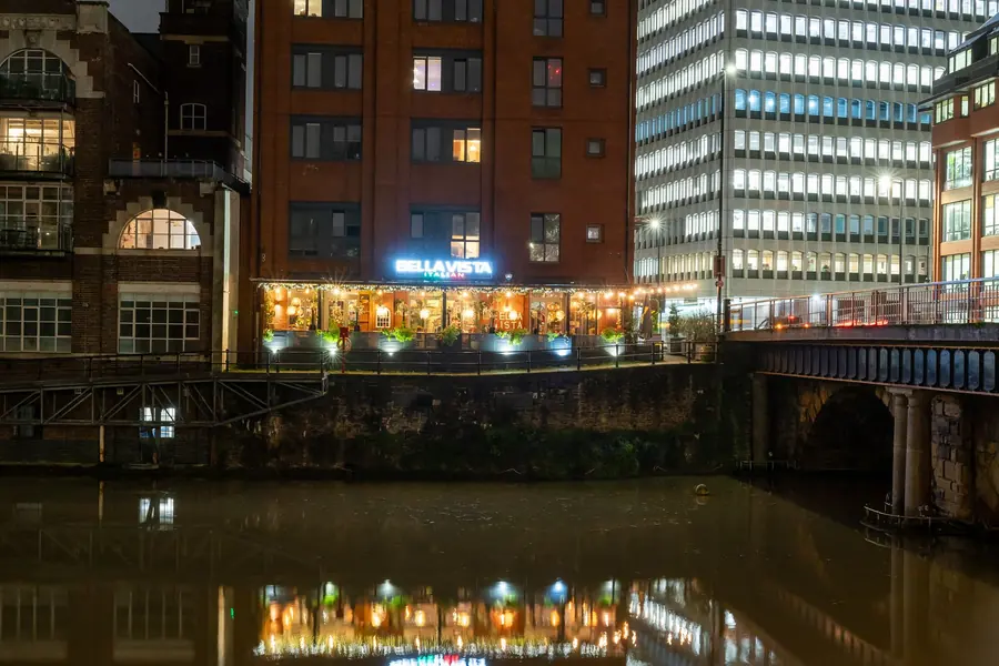 Bella Vista Italian restaurant lit up at night, its terrace reflected in the river, Bristol