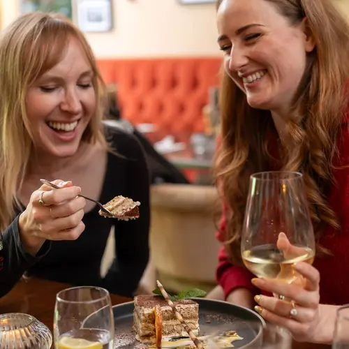 Friends laughing over dessert and wine at Bella Vista, Bristol