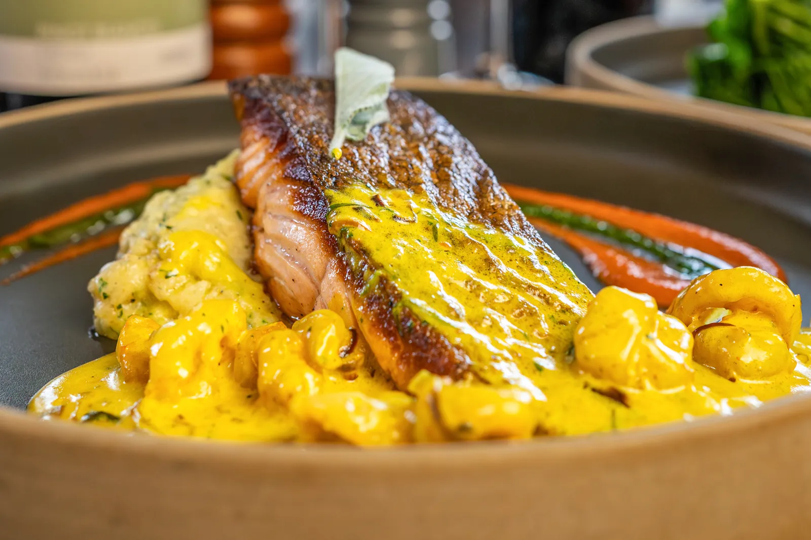 Pan-seared salmon fillet in a golden saffron sauce at Bella Vista Italian restaurant, Bristol